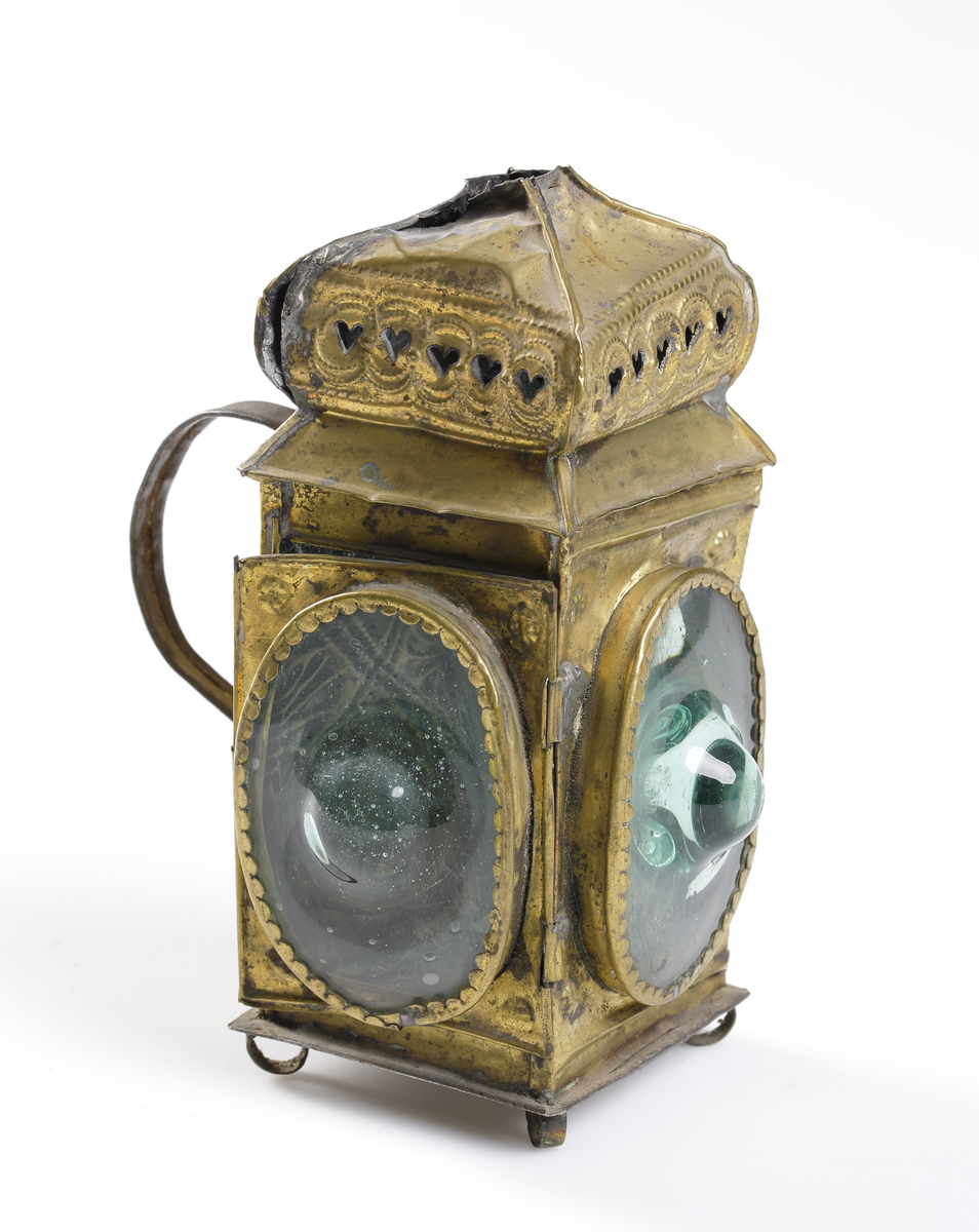 Lykta av ornerad mässing med stansad rökhuv och handtag i bakre sida. Försedd grönkupiga glas. Dörr i sidan med enkel låsfunktion.

Inskrivet i huvudkatalog 1892-1900.