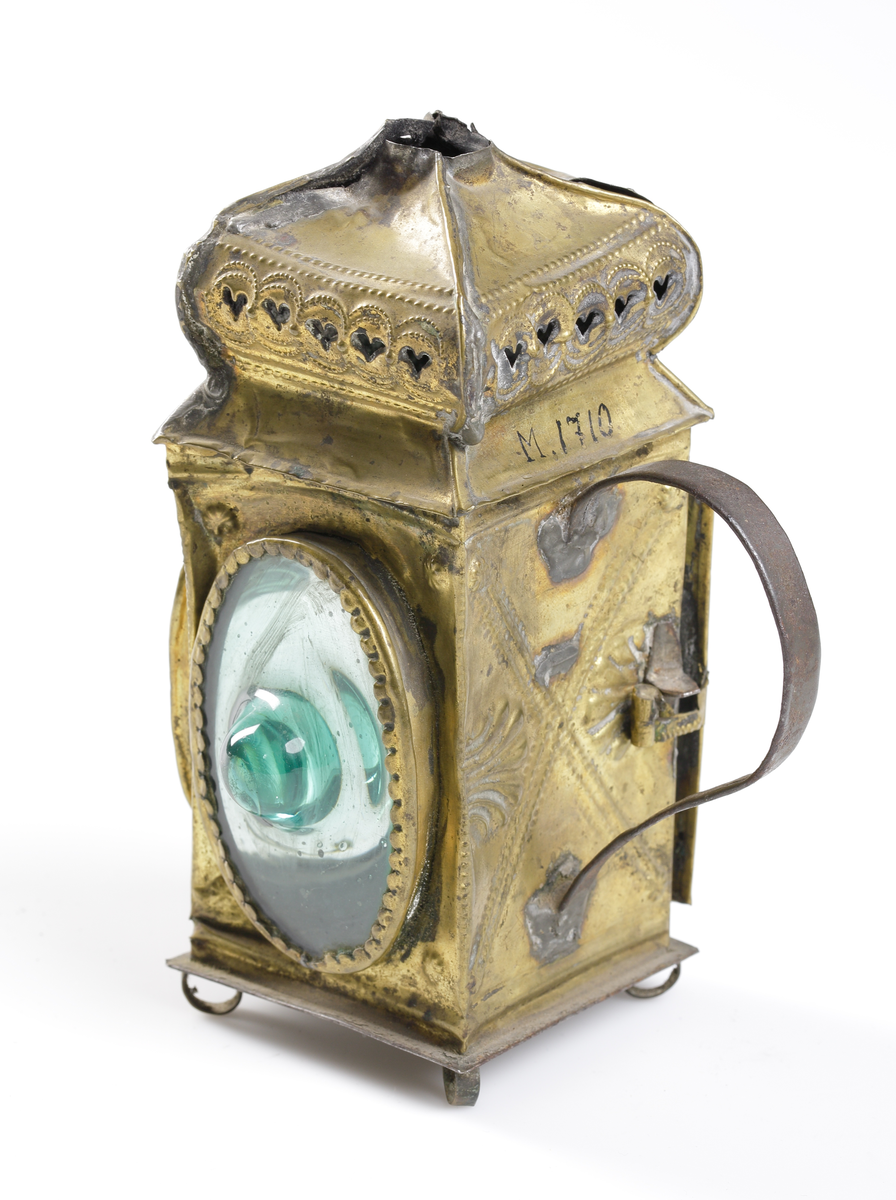 Lykta av ornerad mässing med stansad rökhuv och handtag i bakre sida. Försedd grönkupiga glas. Dörr i sidan med enkel låsfunktion.

Inskrivet i huvudkatalog 1892-1900.