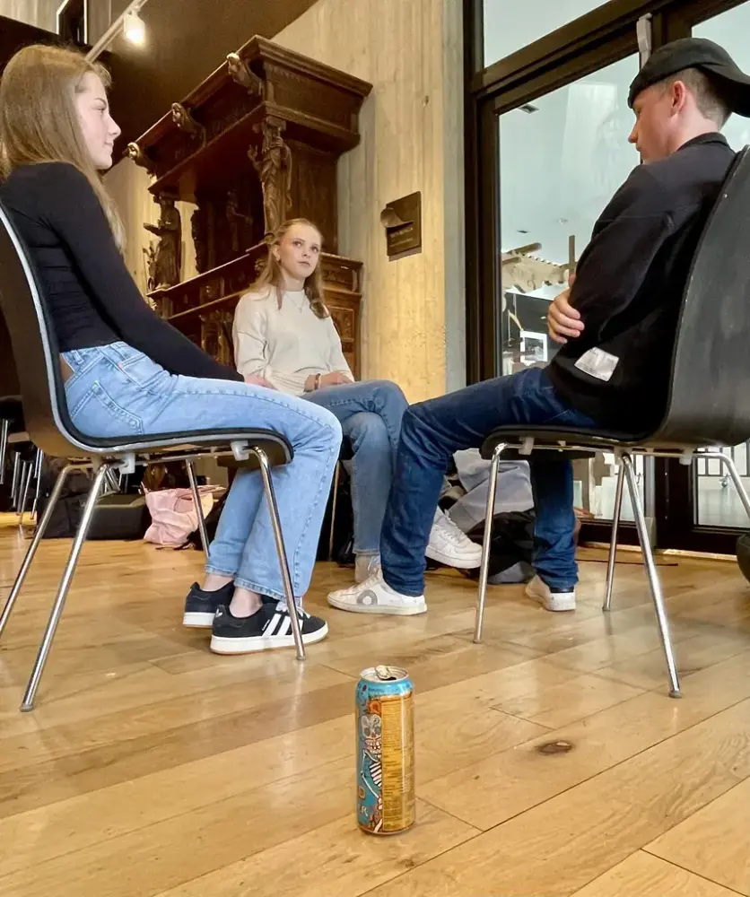 Tre unge som sit og pratar med kvarandre