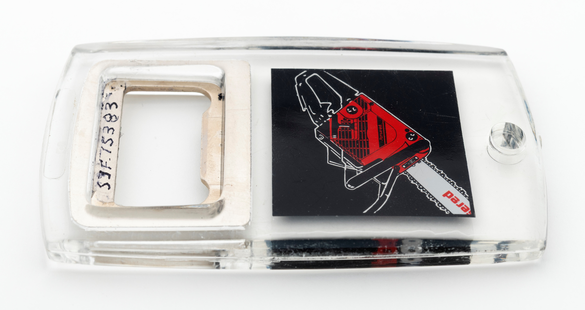 En tilnærmet rektangulær flaskeåpner som hovedsakelig er utført i støpt plast, antatt pleksiglass, med metalltann og påtrykt dekor. Metalltanna, som er støpt inni plasten/pleksiglasset har en rektangulær form. Metalltanna har en "lysåpning" som er cirka 2,6 centimeter lang og 1,4 centimeter bred. Nederst på flaskeåpeneren er det et lite hull slik at den kan henges opp eller festes til en nøkkelreing. 

Under metalltanna er det trykt et bilde av en Jonsered motorsag på den en siden og teksten Jonsered Turbo på den andre siden. Det antas at motorsagmodellen som er avbildet på flaskeåpnerens ene side skal forestille Jonsereds sagmodell 2051 Turbo, men det er ikke bekreftet. 

Flaskeåpneren er en reklameartikkel, et profileringsprodukt, for motorsagmerket Jonsered. Sagmodellen Jonsered 2051 Turbo ble lansert i 1988 og produsert til 1993. Det antas derfor at reklameartikkelen, pofileringsproduktet, ble lansert når disse sagene kom på markedet i 1988.