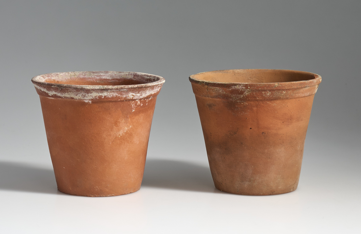 2 blomsterpotter i brent leire. Terrakottapotter med hull under i ca. lik størrelse. Ingen av pottene har jevnt fargemønster, men er alle preget av bruk. De begge har tilnærmet flat bunn.
Potte 02 har en sprekk som løper fra kanten av potten og skrått ned til bunnen.