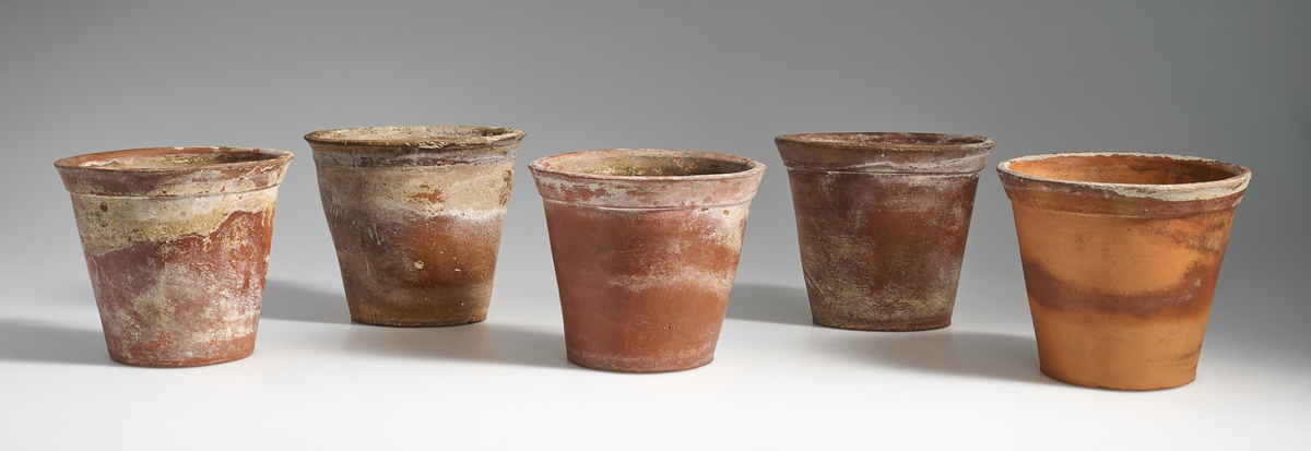 5 blomsterpotter i brent leire. Terrakottapotter med hull under i ca. lik størrelse. Ingen av pottene har jevnt fargemønster, men er alle preget av bruk. 
Pottene 01, 03, 04, og 05, har en liten kant under som danner bunnen av potten, med en flat fordypning under.
Potte 02 har ingen kant under, men har en flat bunn.