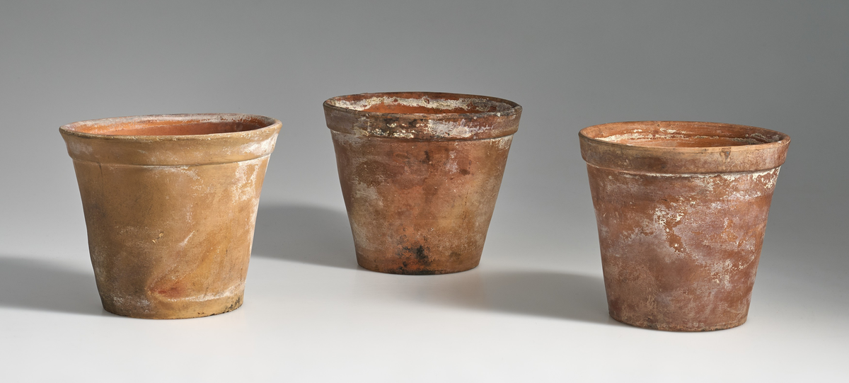 7 blomsterpotter i brent leire. Terrakottapotter med hull under i ca. lik størrelse. Ingen av pottene har jevnt fargemønster, men er alle preget av bruk. 
Pottene 01, 03, 05, 06 og 07, har en liten kant under som danner bunnen av potten, med en flat fordypning under.
Potte 02, har tynnere kant under som ikke er hel, men består av 4 kanter ovenfor hverandre, den er noe lysere i fargen og er markert med tallet "14" under.
Potte 04 har ingen kant under, men har en flat bunn.
Potte 06 har sprekkdannelse under på den ene siden, ovenfor dreneringshullet.