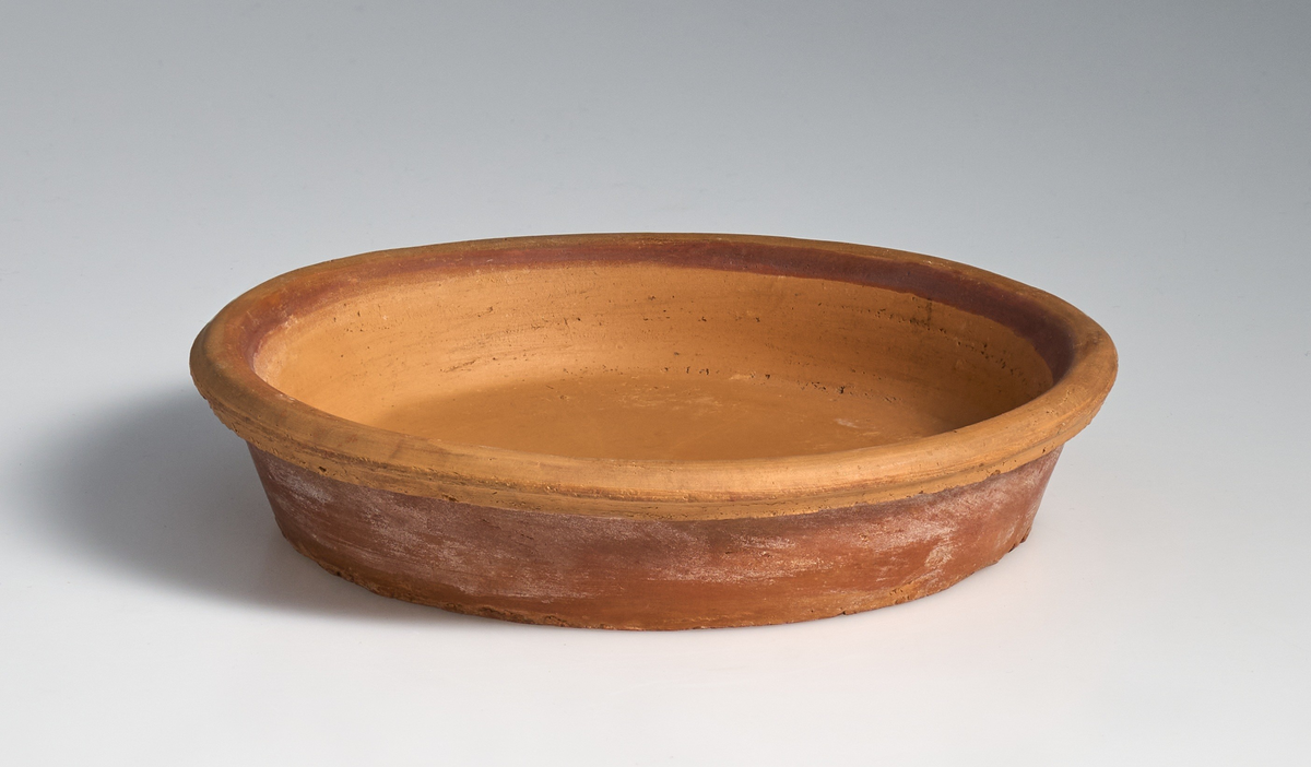 2 fat til blomsterpotter i brent leire. Terrakottafat med sirkulær og tilnærmet flat bunn, med kanter som skråner jevnt opp og utover. Øverste del av kanten rundt er avrundet og strekker seg utover kanten til fatet. Ingen av fatene har jevnt fargemønster, men er alle preget av bruk. Fatet markert med 01 er noe lysere og mer tilnærmet oransje i fargen enn 02. Fatet markert med 02  har noe gråere skjær i fargen.