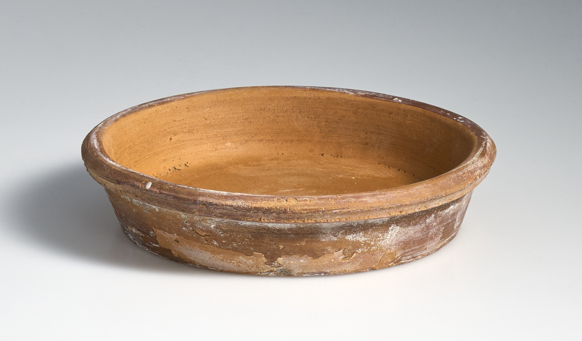 2 fat til blomsterpotter i brent leire. Terrakottafat med sirkulær og tilnærmet flat bunn, med kanter som skråner jevnt opp og utover. Øverste del av kanten rundt er avrundet og strekker seg utover kanten til fatet. Ingen av fatene har jevnt fargemønster, men er alle preget av bruk. Fatet markert med 01 er noe lysere og mer tilnærmet oransje i fargen enn 02. Fatet markert med 02  har noe gråere skjær i fargen.