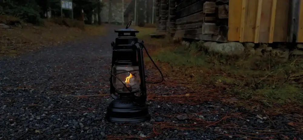 Gammal ljuslykta i mörkret utanför gammalt timrat hus