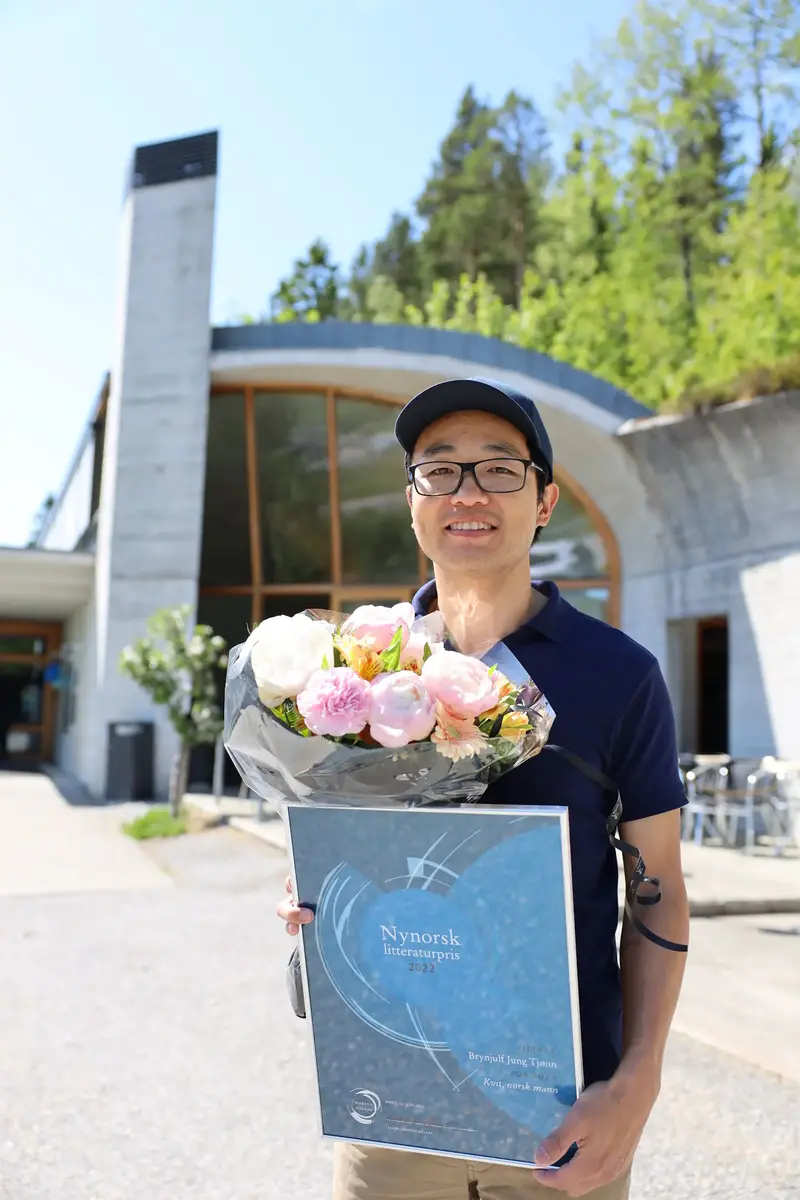 Brynjulf Jung Tjønn med diplomet for Nynorsk litteraturpris 2022 og ein blomsterbukett, utanfor Aasentunet