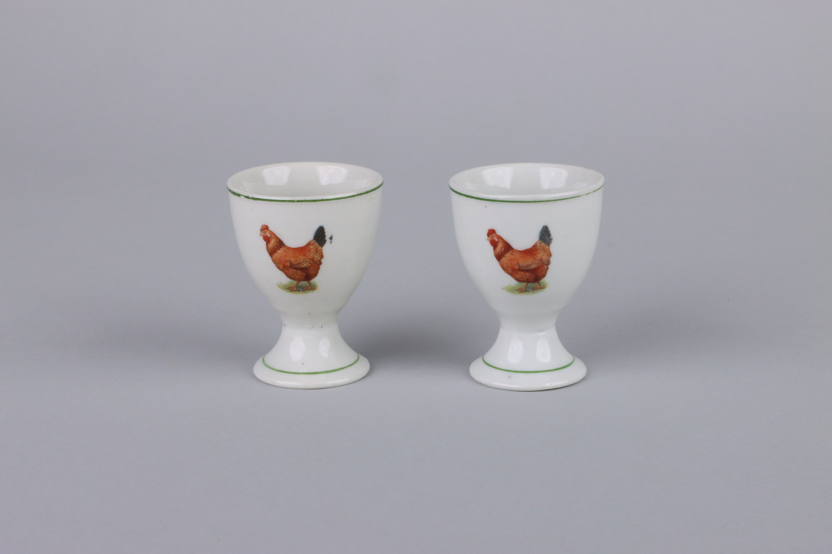 Äggkoppar på fot med rund form. Utsidan av kopparna har dekor med en höna. Upptill vid mynningen och nere runt foten en grön linje som går runt om kopparna. Insidan av äggkopparna är odekorerad. Undersidan av foten är oglaserad.