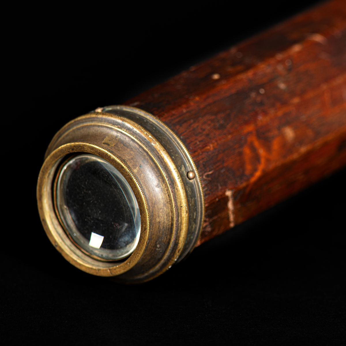 10 kantig tubkikare med träbefattning (troligtvis av mahogny) och mässingsfäste på vardera kortände. Glaslinsen saknas fram.