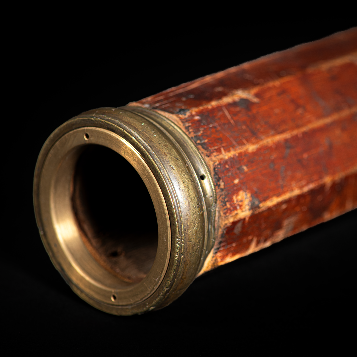 10 kantig tubkikare med träbefattning (troligtvis av mahogny) och mässingsfäste på vardera kortände. Glaslinsen saknas fram.