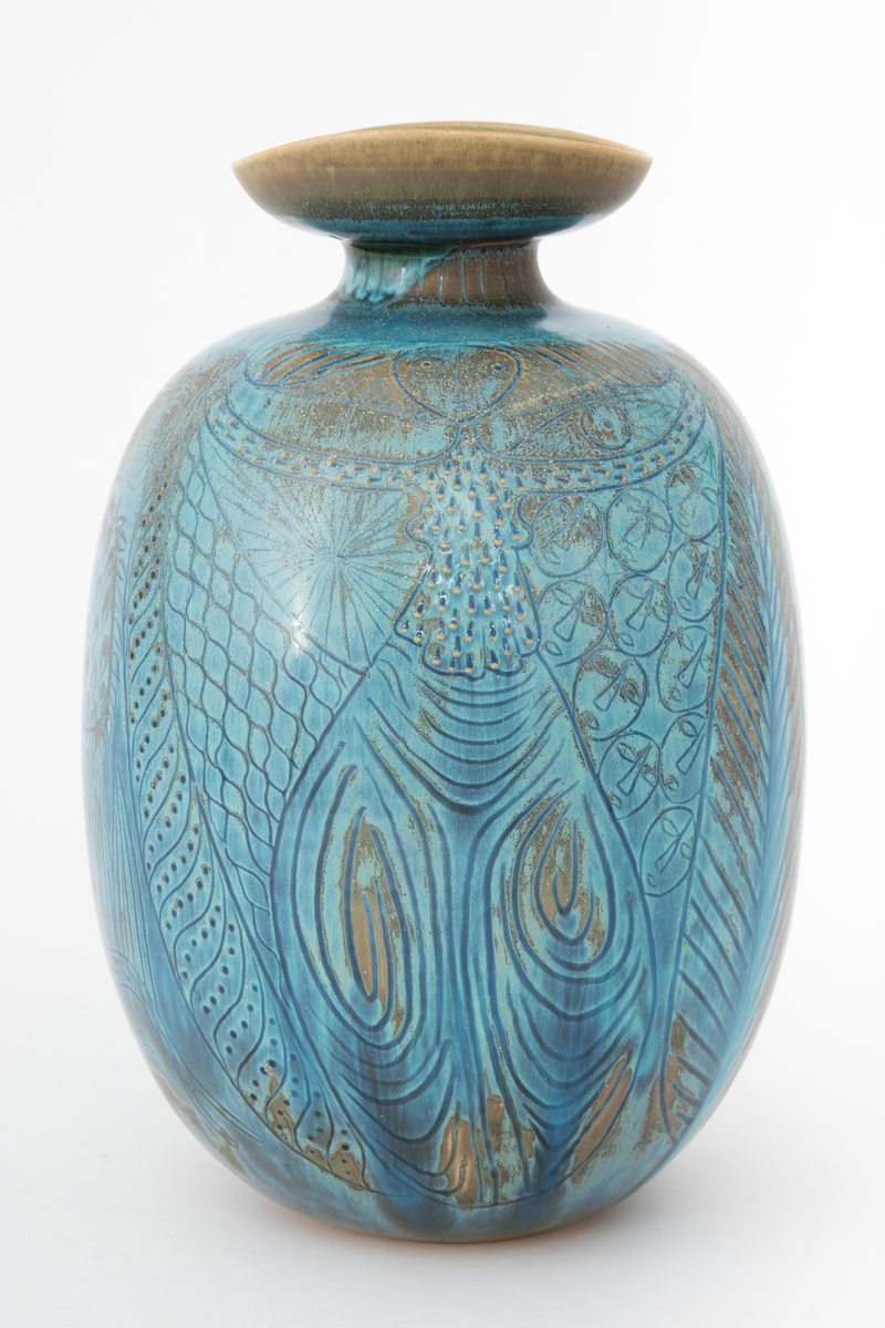 Krukke i steingods. Oval korpusform og kort innsnevret hals med vid, skålformet krage om munningen. Dekket med glasur i blå nyanser med overganger mot grågrønt. Innrisset dekor forestillende en kvinne i halvfigur, hus, tre, fisk samt en kvinne i helfigur mot en mønstret bakgrunn med ovaler og små ansikter.