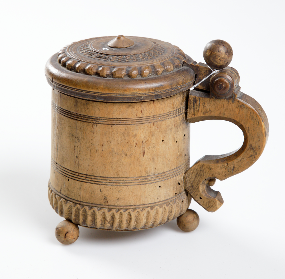 Stånka av trä, cylindriskt svarvad och med skuren dekor. Med gängat fällock och profilerat handtag. Stående på tre kulfötter.

Inskrivet i huvudkatalog 1933.