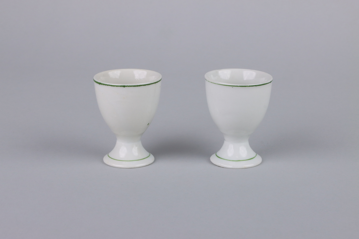 Äggkoppar på fot med rund form. Utsidan av kopparna har dekor med en höna. Upptill vid mynningen och nere runt foten en grön linje som går runt om kopparna. Insidan av äggkopparna är odekorerad. Undersidan av foten är oglaserad.