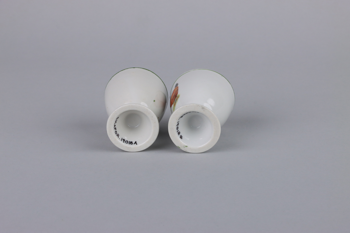 Äggkoppar på fot med rund form. Utsidan av kopparna har dekor med en höna. Upptill vid mynningen och nere runt foten en grön linje som går runt om kopparna. Insidan av äggkopparna är odekorerad. Undersidan av foten är oglaserad.