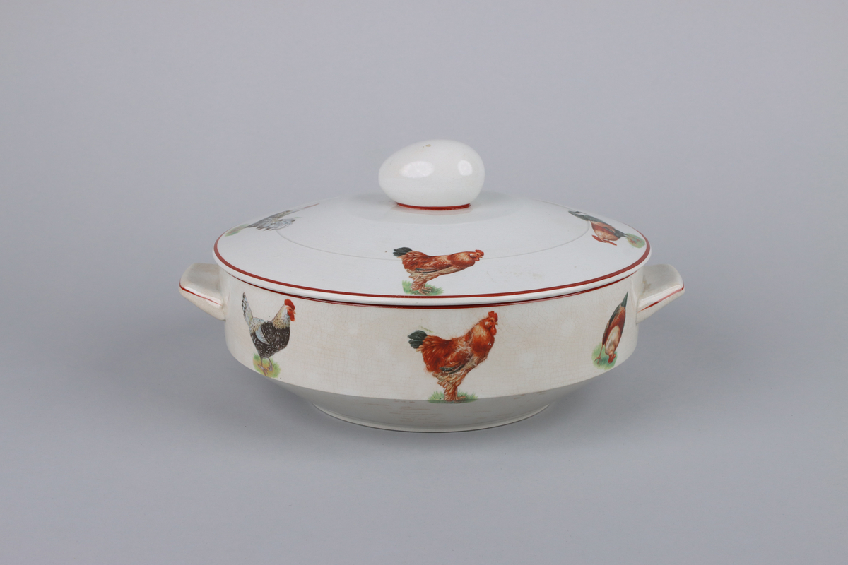 Äggterrin med lock, rund form och raka sidor. Locket är krönt upptill med ett handtag i form av ett ägg. På terrinens sidor finns två månghörnande hänklar dekorerade med röda linjer, nedtill en indragen midja och under en låg fotring. Upptill runt om handtagets fäste en röd kant, kring lockets och terrinens kant löper röda raka bårder  På locket och skålens sidor dekor av höns och tuppar i olika raser. Under skålen fabriksstämpel med Gefle i skrivstil. Insidan av terrinen är odekorerad.


