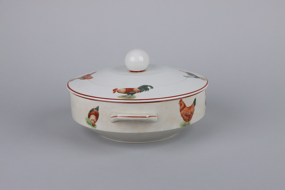 Äggterrin med lock, rund form och raka sidor. Locket är krönt upptill med ett handtag i form av ett ägg. På terrinens sidor finns två månghörnande hänklar dekorerade med röda linjer, nedtill en indragen midja och under en låg fotring. Upptill runt om handtagets fäste en röd kant, kring lockets och terrinens kant löper röda raka bårder  På locket och skålens sidor dekor av höns och tuppar i olika raser. Under skålen fabriksstämpel med Gefle i skrivstil. Insidan av terrinen är odekorerad.


