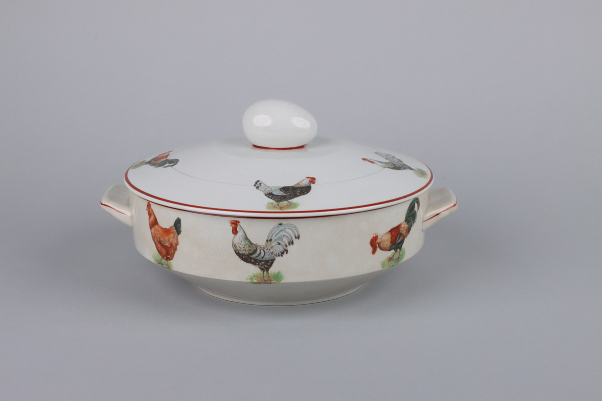 Äggterrin med lock, rund form och raka sidor. Locket är krönt upptill med ett handtag i form av ett ägg. På terrinens sidor finns två månghörnande hänklar dekorerade med röda linjer, nedtill en indragen midja och under en låg fotring. Upptill runt om handtagets fäste en röd kant, kring lockets och terrinens kant löper röda raka bårder  På locket och skålens sidor dekor av höns och tuppar i olika raser. Under skålen fabriksstämpel med Gefle i skrivstil. Insidan av terrinen är odekorerad.


