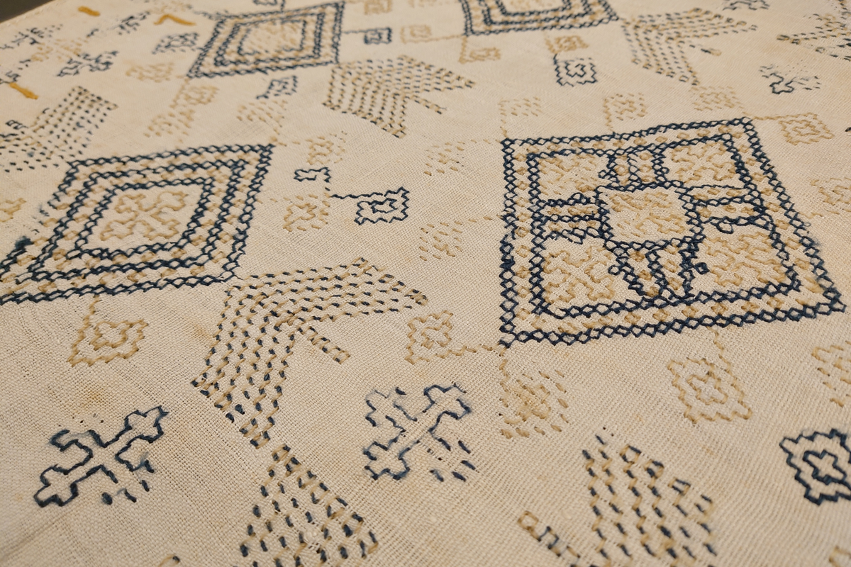 Julehandkle i grov lin med 15 cm brei firflettingsbord i nedre enden. Over heile handkledet er det brodert mønster i holbeinsting i blått og lys gulbrunt ullgarn. Enkelte plassar er ulltråden borte, slik at det står att berre merke etter den. Øverst på handkledet er det brodert 1774 (?) og bokstavane ILDV (?) i kjedesting. Desse er brodert med eit tjukkare ullgarn i gult.
Handkledet er falda i øvrekanten. og det er jarekantar i sidene.
I kanten øverst er det påsydd tre små hemper for å henga opp handkledet. Fint stoppa i endane øverst.