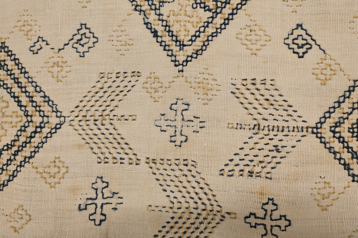 Julehandkle i grov lin med 15 cm brei firflettingsbord i nedre enden. Over heile handkledet er det brodert mønster i holbeinsting i blått og lys gulbrunt ullgarn. Enkelte plassar er ulltråden borte, slik at det står att berre merke etter den. Øverst på handkledet er det brodert 1774 (?) og bokstavane ILDV (?) i kjedesting. Desse er brodert med eit tjukkare ullgarn i gult.
Handkledet er falda i øvrekanten. og det er jarekantar i sidene.
I kanten øverst er det påsydd tre små hemper for å henga opp handkledet. Fint stoppa i endane øverst.