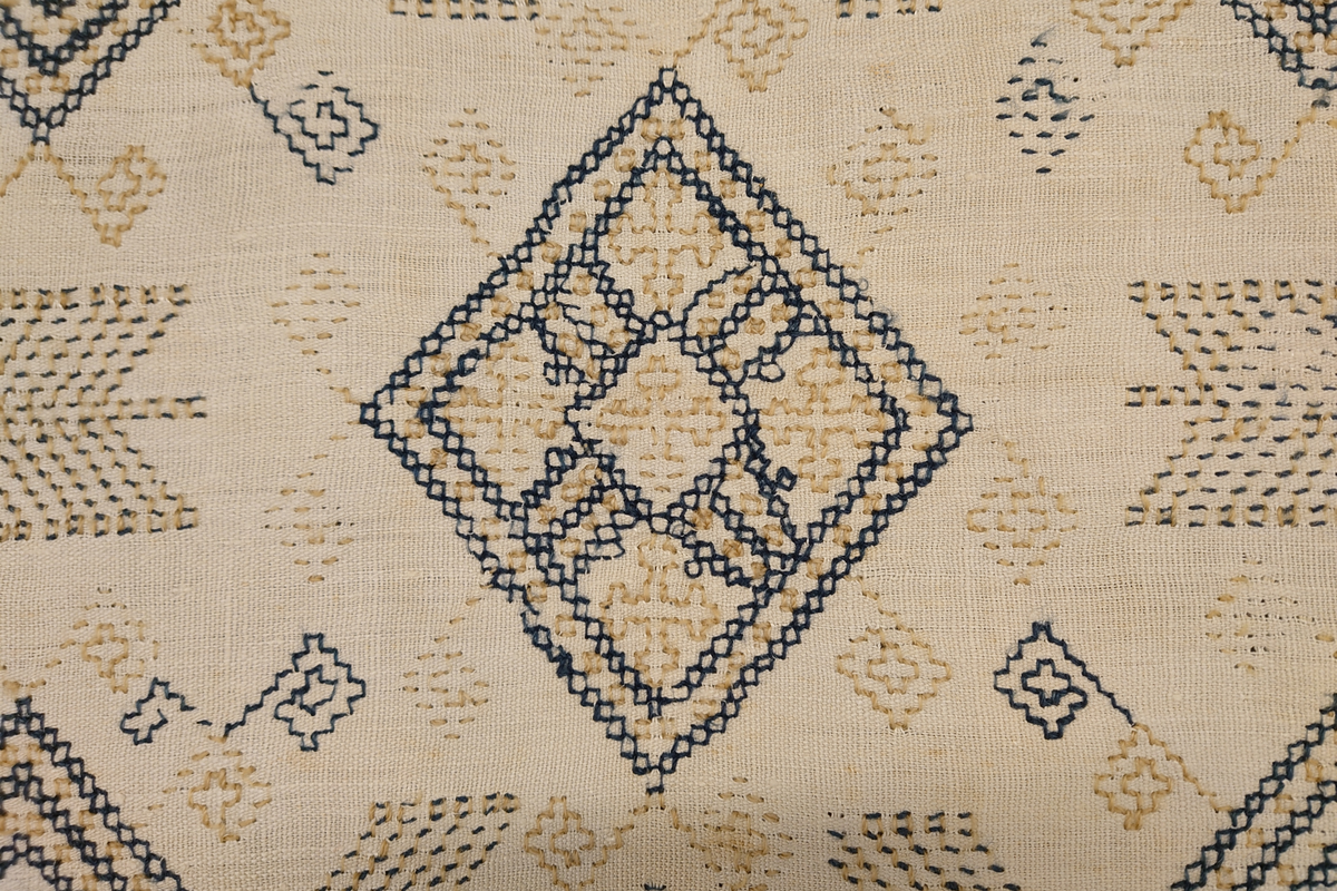 Julehandkle i grov lin med 15 cm brei firflettingsbord i nedre enden. Over heile handkledet er det brodert mønster i holbeinsting i blått og lys gulbrunt ullgarn. Enkelte plassar er ulltråden borte, slik at det står att berre merke etter den. Øverst på handkledet er det brodert 1774 (?) og bokstavane ILDV (?) i kjedesting. Desse er brodert med eit tjukkare ullgarn i gult.
Handkledet er falda i øvrekanten. og det er jarekantar i sidene.
I kanten øverst er det påsydd tre små hemper for å henga opp handkledet. Fint stoppa i endane øverst.