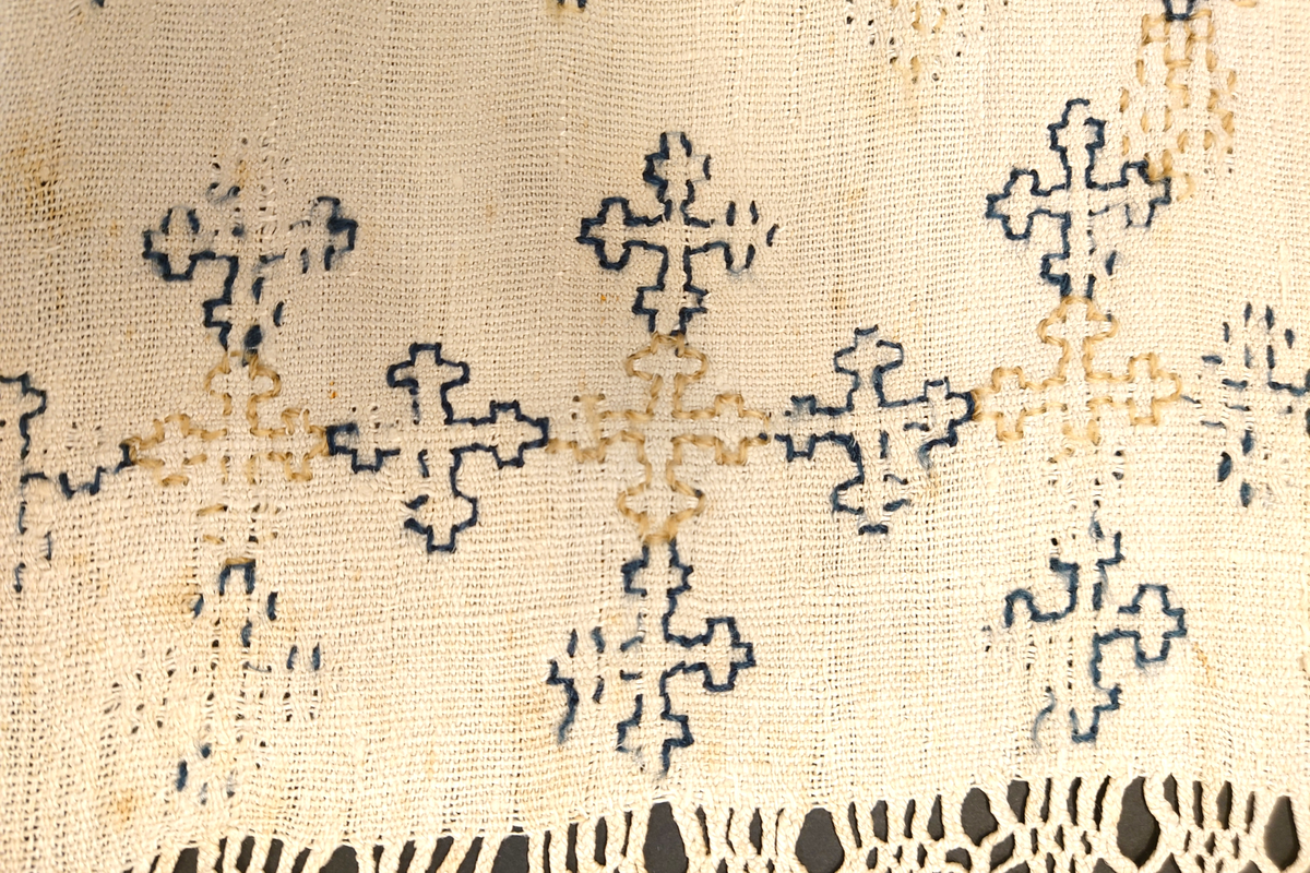 Julehandkle i grov lin med 15 cm brei firflettingsbord i nedre enden. Over heile handkledet er det brodert mønster i holbeinsting i blått og lys gulbrunt ullgarn. Enkelte plassar er ulltråden borte, slik at det står att berre merke etter den. Øverst på handkledet er det brodert 1774 (?) og bokstavane ILDV (?) i kjedesting. Desse er brodert med eit tjukkare ullgarn i gult.
Handkledet er falda i øvrekanten. og det er jarekantar i sidene.
I kanten øverst er det påsydd tre små hemper for å henga opp handkledet. Fint stoppa i endane øverst.