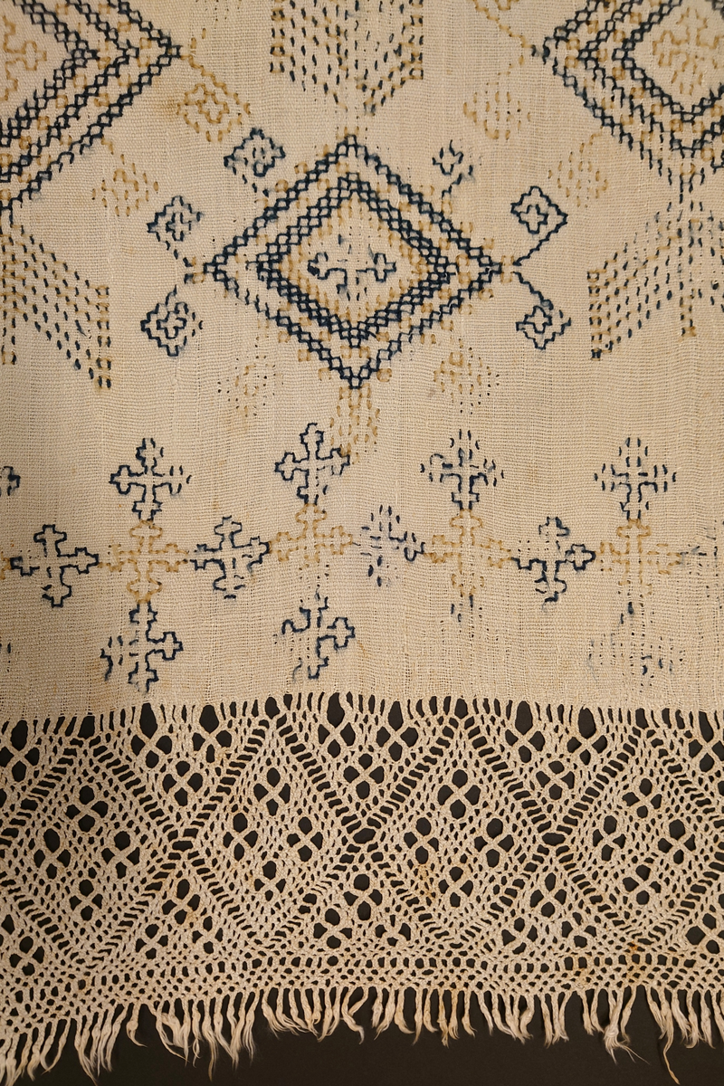 Julehandkle i grov lin med 15 cm brei firflettingsbord i nedre enden. Over heile handkledet er det brodert mønster i holbeinsting i blått og lys gulbrunt ullgarn. Enkelte plassar er ulltråden borte, slik at det står att berre merke etter den. Øverst på handkledet er det brodert 1774 (?) og bokstavane ILDV (?) i kjedesting. Desse er brodert med eit tjukkare ullgarn i gult.
Handkledet er falda i øvrekanten. og det er jarekantar i sidene.
I kanten øverst er det påsydd tre små hemper for å henga opp handkledet. Fint stoppa i endane øverst.