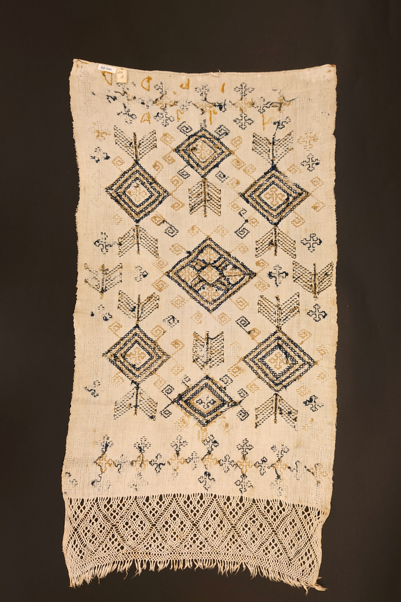 Julehandkle i grov lin med 15 cm brei firflettingsbord i nedre enden. Over heile handkledet er det brodert mønster i holbeinsting i blått og lys gulbrunt ullgarn. Enkelte plassar er ulltråden borte, slik at det står att berre merke etter den. Øverst på handkledet er det brodert 1774 (?) og bokstavane ILDV (?) i kjedesting. Desse er brodert med eit tjukkare ullgarn i gult.
Handkledet er falda i øvrekanten. og det er jarekantar i sidene.
I kanten øverst er det påsydd tre små hemper for å henga opp handkledet. Fint stoppa i endane øverst.