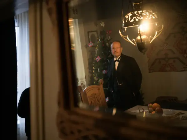 En mann i smoking står foran et juletre i en leilighet innredet som i 1905 i OBOS-gården Wesselsgate 15 på Norsk Folkemuseum. 