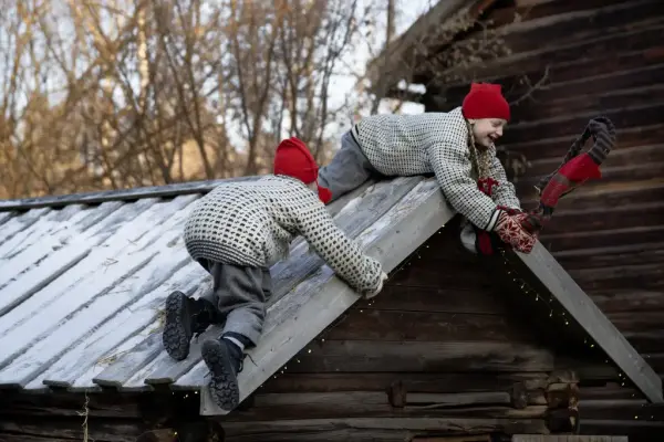 To rampenisser har klatret opp på taket på et lite hus på Norsk Folkemuseum. 