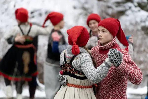 Dansere fra Norsk Folkemuseums dansegruppe danser folkedans i ført setesdalsbunader og nisseluer. 