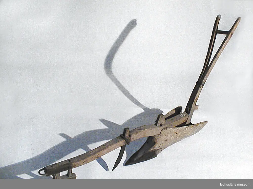 Träårder med smidd plogbill som kopplas till ett dragok. 
Dragårdret sammanhör med Drakok, UM027773

Ur handskrivna katalogen 1957-1958:
Årder att dragas för hand
L. c:a 152 cm. Järnbeslag. Dragträ l. m. kätting. Föremål. Järnet ngt rostigt. Träet maskätet.