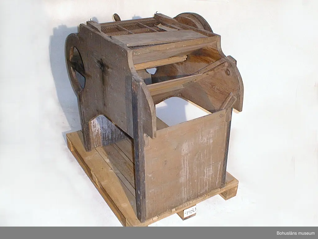 Ur handskrivna katalogen 1957-1958:
Sädesharpa
L. 124; Br. 61; H. 100 cm (drivhjulen oräknade). b) En sikt som avskiljer olika storlekar av korn 49,5 x 52,5 cm; träram m. parallella trådar av järn. Rost. Hel.

Lappkatalog: 51