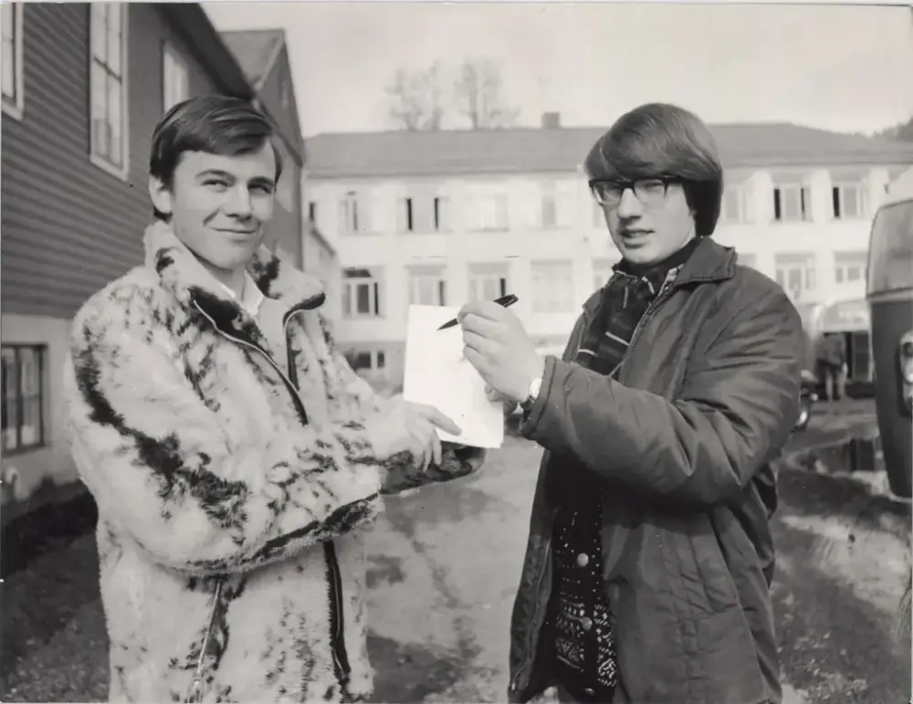 Ottar Wiik og Knut O. Dahle står ute i vinterjakker og held ei skrivebok og ein penn.