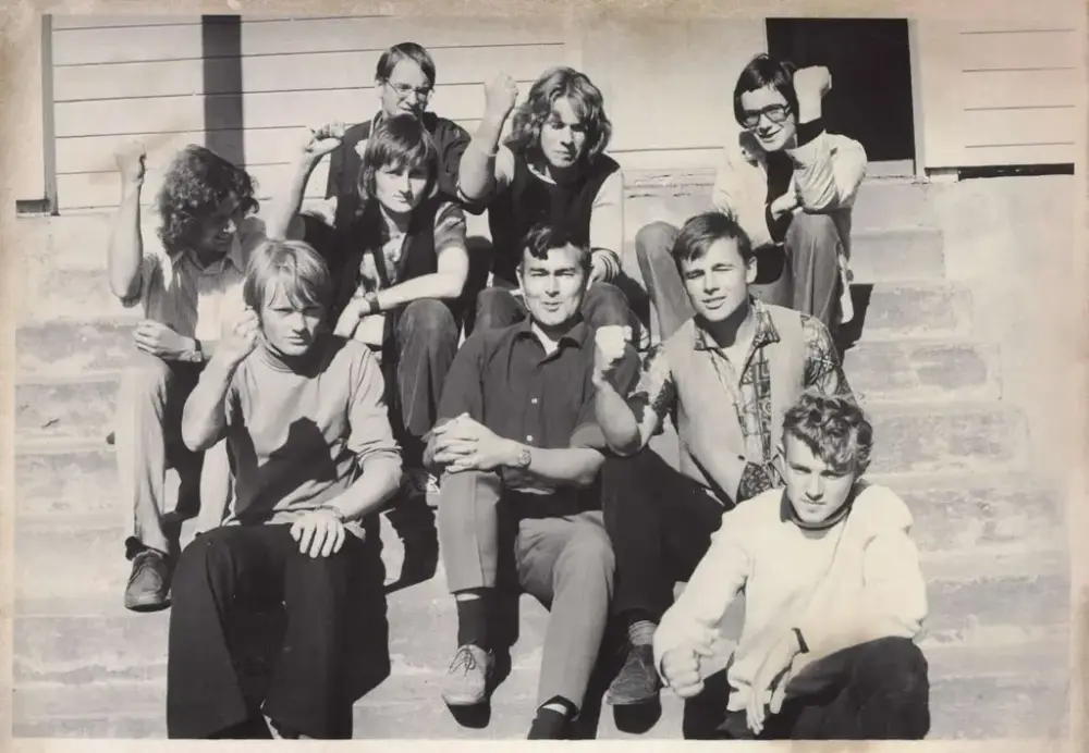 Ei gruppe demonstrantar sit med kvar sin arm lyfta og knytt neve, ute på ei betongtrapp