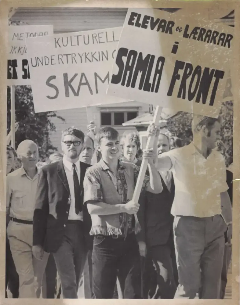 Eit utstnitt frå ein demonstrasjon der ei gruppe demonstrantar held oppe banner ulike tekstar for nynorske læremiddel i skulen.