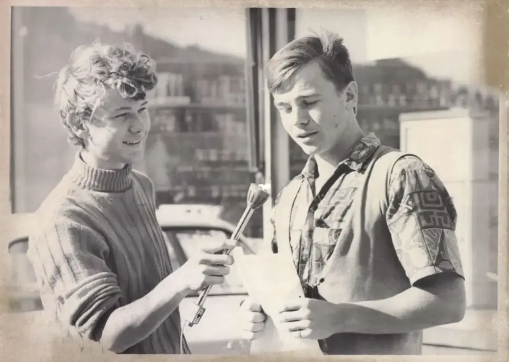 Ottar Wiik står framom eit butikkvindauge og held ein tale medan ein annan gut held ein mikrofon for han