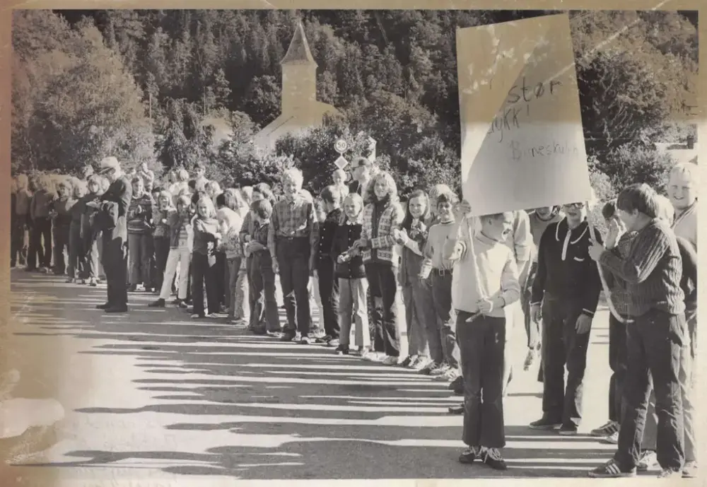 Elevar ved barneskulen i Øystese står samla ute, og to unge gutar som står fremst held eit banner med påskrifta «Vi stør dykk. Barneskulen.»