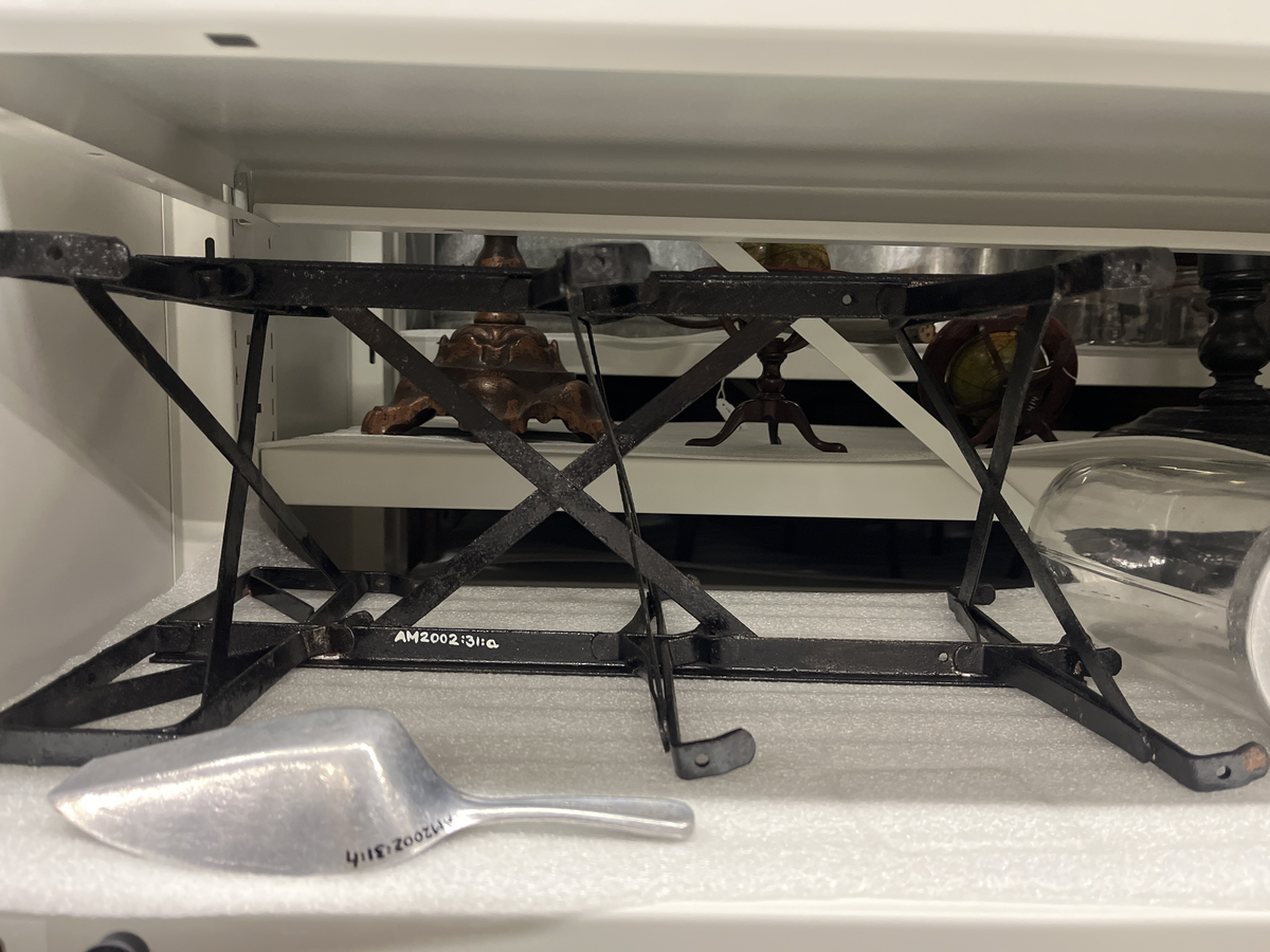 Ställ och glasbehållare för försäljning av karameller. 
a. Svart metallställning.
b-g. Glasbehållare med lock av aluninium. Locken öppnas genom att fällas ner. Text på några av locken "DIX Miniatyr AB JOHN FRÖBERG FINNSPÅNG".
h. Skopa av alumunium.

Från Arne Ekströms handelsmuseum.