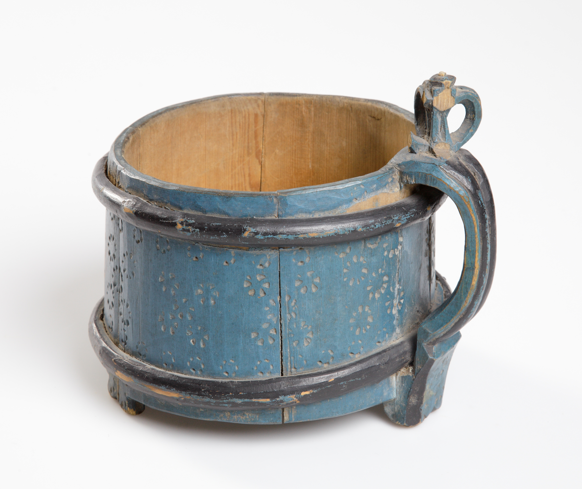 Trästånka med enkel glödritad ornering, blåmålad. Försedd med två träband samt handtaget delvis svartmålat. Saknar lock.

Inskrivet i huvudkatalog 1929.