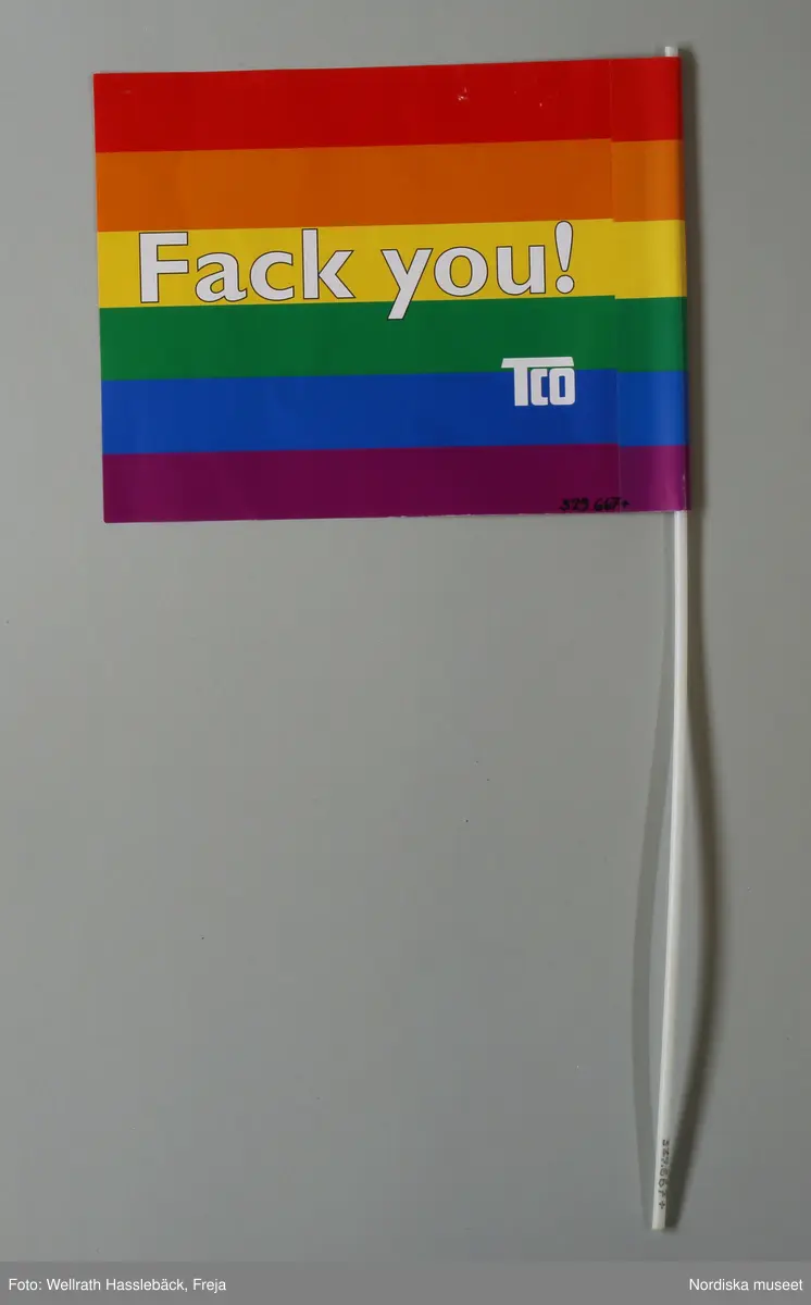 Flagga med pinne. Flaggan av papper med tryck. På framsidan text "Fack you / TCO" mot bakgrund av horisontala ränder i färgerna (uppifrån och ner) rött, orange, gult, grönt, blått och lila, de s.k. regnbågsfärgerna. Flaggan är i ena änden klistrad så att en kanal bildas där en pinne av vit, ihålig plast, skjuts in. 

Färgerna är de s.k. regnbågsfärgerna som ingår i regnbågsflaggan, som ofta används som symbol för HBT-tillhörighet. Även flaggans rosa baksida ska syfta på HBT-tillhörighet då den rosa färgen också ofta används som symbol för just detta.

Flaggan ingår i Nordiska museets dokumentation av Stockholm Pride / Europride 2008. Stockholm Pride är den största årliga festivalen för HBT-personer i Sverige och som 2008 firades 25 jul.-3 aug. Detta år var Stockholm Pride även värd för Europride. Pridefirandet är framför allt uppdelat på två platser, Pride House (år 2008 i Kulturhuset) och Pride Park (i Tantolunden). Flaggan delades ut av TCO (Tjänstemännens centralorganisation)  i de tält de delade med Socialdemokraterna i Pride Park. 

Flaggan är ett exempel på hur många företag och organisationer anpassar sina marknadsföreingsprodukter efter vilka man riktar sig till. "Fack you" ska ge associationer till Fuck You, och sådana tvetydiga syftningar på sex är inte ovanliga när man vänder sig till HBT-personer. 

Föremålet ingår i Nordiska museet dokumentation av Europride/Stockholm Pride 2008 med intervjuer, fotografier och föremål. Se vidare arkivet (D.457).
/Leif Wallin 2009-05-14