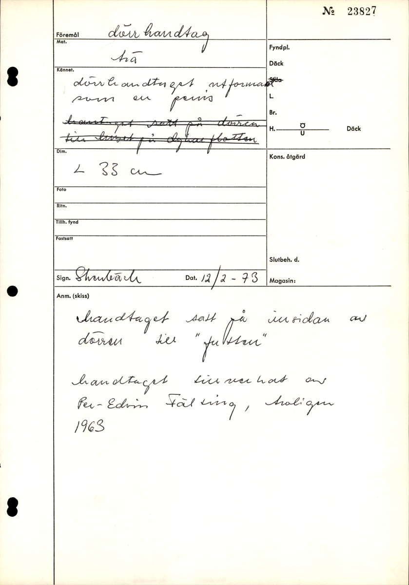 Täljt handtag av trä, utformat som en fallos. Två spikhål vid fästet.