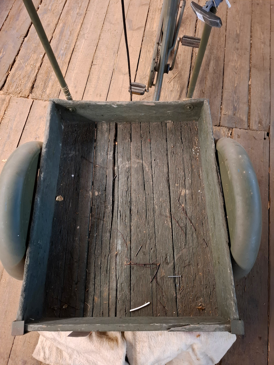 Militärgrön lådcykel av märke Monark med svarta hjul och brun lädersadel. Lådan är placerad i cykelns främre del och stabiliseras med två hjul. Styret består av en rektangulär ram monterad på lådans bakre del. Den bakre delen av cykeln ser ut som en helt vanlig cykel. 

I lådan ligger två tjocka vit-beige fleecefiltar. De båda filtarna är sydda som rektangulära påsar. I lådan finns också ett lås med texten "OPTIMUS ILCO", nyckel med texten "OPTIMUS" och kedja. 

På lådans framsida finns sex stycken handritade maritima singalflaggor på papper i olika utföranden som häftats på lådans främre del. Flaggorna ser ut att vara ritade med färgpennor/kritor. Flaggorna från vänster till höger-  
1. Gul och blå (Lodrätt):  Signalflagga K (Kilo) betyder: "Jag vill upprätta förbindelse med er".
2. Gult kryss mot röd bakgrund: Signalflagga R (Romeo) betyder: "Mitt fartyg gör ingen fart genom vattnet".
3. Gul med svart cirkel: Signalflagga I (India) betyder: "Jag ändrar min kurs babord hän".
4. Blå fyrkant mot vit bakgrund: Signalflagga S (Sierra) betyder: "Min maskin går back".
5. Blå fyrkant mot vit bakgrund: Signalflagga S (Sierra) betyder: "Min maskin går back"
6. Blå och röd (vågrätt): Signalflagga E (Echo) betyder: "Jag ändrar kurs styrbord hän".
Bokstäverna stavar tillsammans ordet "KRISSE".

Alla hjul lådcykeln behöver pumpas/lagas. Lådan i trä är också i någerlunda kritiskt skick.