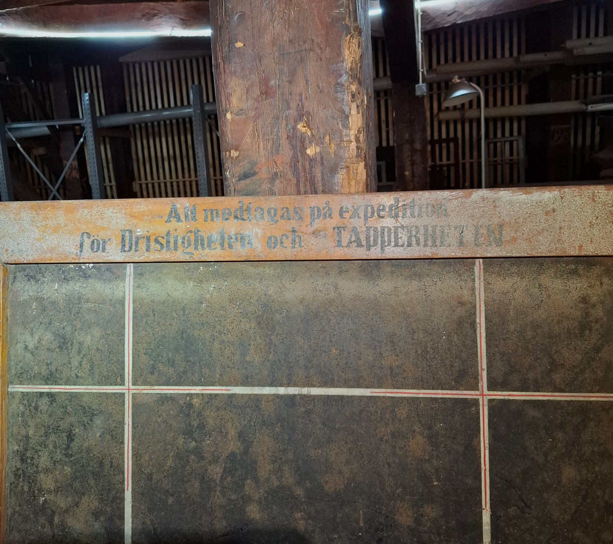 Griffeltavla för planering. Infattad i kraftig träram och sträv svart bakgrund. På tavlan finns vit- och röda streck i både vågrät och lodrätt riktning. På träramens övre del finns texten "Att medtagas på expedition för Dristigheten och TAPPERHETEN" i svart färg. På den nedre delen av tavlan står "TAPPEHETEN" i vit text mot den svarta bakgrunden. 

På tavlans baksidan finns en likadan svart 
tavelbakgrund med två treck i vit och röd färg placerade i ett kors.I lodrät rikning står texten "Dristigheten" i vit färg, placerad nedifrån och upp.