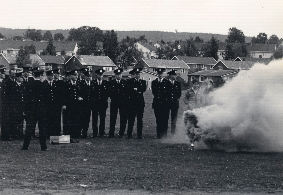 Politifolk og politiryttere på en åpen plass. Publikum. Røyksignal? Trolig en oppvisning e.l.