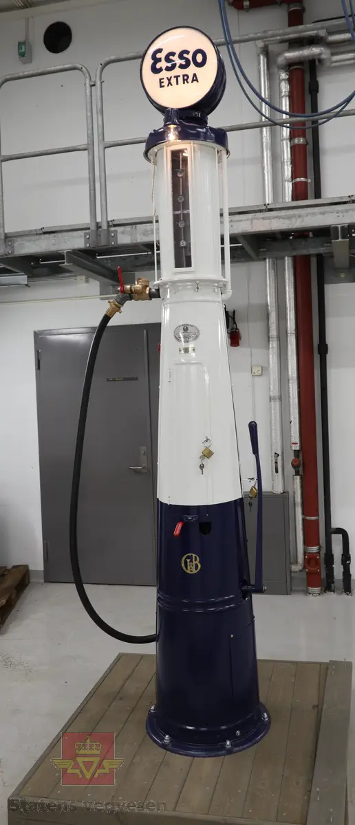 Hånddrevet pumpe, med kuppel på toppen. Kuppelen har en 220 volt lyspære. Pumpa står på en hjemmelagd sokkel av tre (det gjør den stødig og flyttbar). Maks. fyllekvantum om gangen er 20 liter. Pumpa har et skilt som viser at den ble kontrollert i 1950. Ved restaureringen ble alt tatt fra hverandre og reparert til tilnærmet ny tilstand. Kuppelen ble lagd ny. Pumpa grunnet med Owatrol og lakkert med oljemaling (Bengalakk). Fargekoder: Hvit: RAL 9016 Verkehrsweiss. Blå mørk: RAL 5013 Kobaltblau. Blå lys innvendig: RAL 5024 Pastellblau. (tatt fra et tysk RAL-kart).