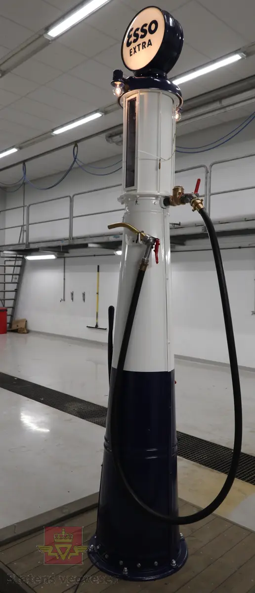 Hånddrevet pumpe, med kuppel på toppen. Kuppelen har en 220 volt lyspære. Pumpa står på en hjemmelagd sokkel av tre (det gjør den stødig og flyttbar). Maks. fyllekvantum om gangen er 20 liter. Pumpa har et skilt som viser at den ble kontrollert i 1950. Ved restaureringen ble alt tatt fra hverandre og reparert til tilnærmet ny tilstand. Kuppelen ble lagd ny. Pumpa grunnet med Owatrol og lakkert med oljemaling (Bengalakk). Fargekoder: Hvit: RAL 9016 Verkehrsweiss. Blå mørk: RAL 5013 Kobaltblau. Blå lys innvendig: RAL 5024 Pastellblau. (tatt fra et tysk RAL-kart).