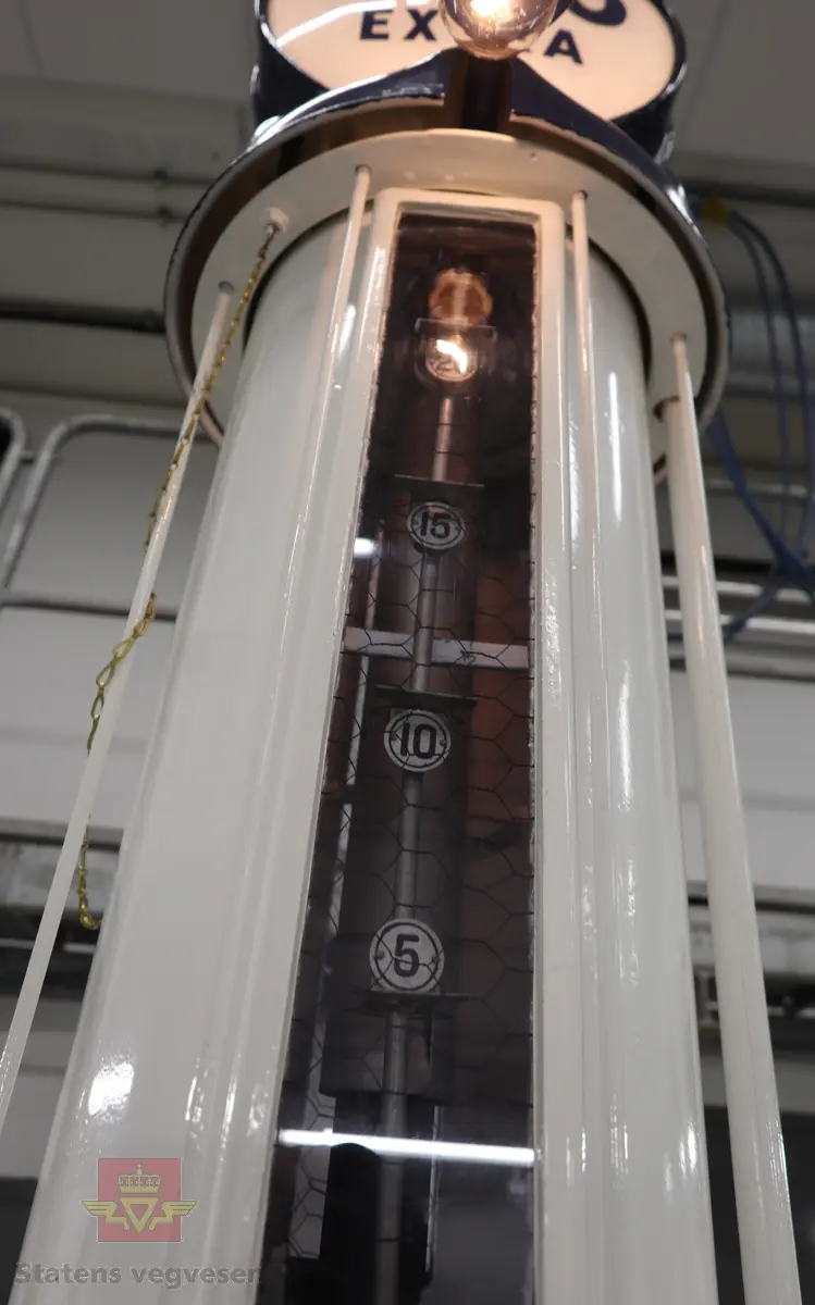 Hånddrevet pumpe, med kuppel på toppen. Kuppelen har en 220 volt lyspære. Pumpa står på en hjemmelagd sokkel av tre (det gjør den stødig og flyttbar). Maks. fyllekvantum om gangen er 20 liter. Pumpa har et skilt som viser at den ble kontrollert i 1950. Ved restaureringen ble alt tatt fra hverandre og reparert til tilnærmet ny tilstand. Kuppelen ble lagd ny. Pumpa grunnet med Owatrol og lakkert med oljemaling (Bengalakk). Fargekoder: Hvit: RAL 9016 Verkehrsweiss. Blå mørk: RAL 5013 Kobaltblau. Blå lys innvendig: RAL 5024 Pastellblau. (tatt fra et tysk RAL-kart).