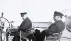 Två män med skepparmössor ombord på ångjakten Tritonia. Text i album: 