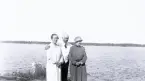 En man som håller om två kvinnor med hav i bakgrunden någonstans i Öregrund. Text i album: 