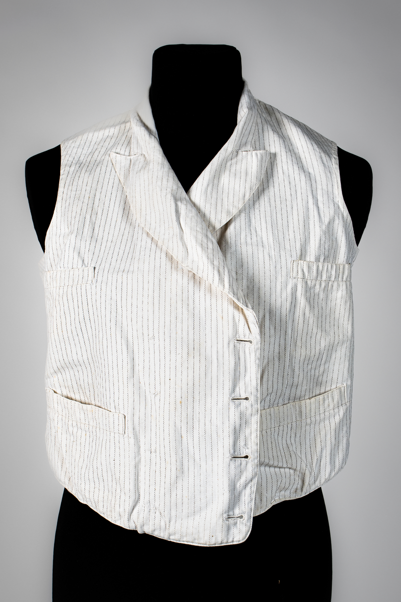 Väst som hör till uniformen som användes av marinläkaren Anders Rudolf Prag.
Anders Prag kom tili Karlskrona 1929 som marinläkare, dispensärläkare och privatpraktiserande läkare, där hans största intresse alltid varit pediatriken, hans huvudintresse och specialitet. Anders Prag har här i staden gjort ett verkligt pionjärarbete i det att han startat barnavårdscentralsverksamheten, om vilken han aven hallit föreläsningar i Karlskrona läkareforening. I föreningen har han varit sekreterare och ordförande. Som marinläkare har Anders nått l:e marinläkargraden. De gåger han underhillit kollegerna med sång till luta, då hans sonora stamma klingat så vackert har varit verkliga högtidsstunder (ur Karlskrona Lakareförening 120 år Från hot om prygelstraff till fastställd arbetstid, SVEN SVENNERUD och HOLGER HOLMGREN 1978). "Gradbeteckningar med olikfärgat kläde mellan galonerna för civilmilitära tjänstemän med specialutbildning inom marinen; rött för marinläkare, vitt för marinintendent och lila för mariningenjör." S. 23 Flottans sjöofficersuniformer i Sjöhistoriska museets samlingar. Nils-Erik Melinder. Sida 38, samma skrift: "Från år 1937, utformades den för sjöofficeraren runda öglan till en rundad triangulär ögla, dessutom poängterad med olikfärgat kläde mellan galonerna. Statusen blev civilmilitär. Ett sammanhängande "öknamn" för den officerskategorin blev därför "päronklubben."